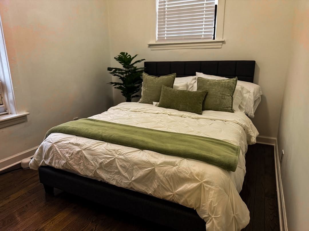 Clean bedroom with made bed and green pillows